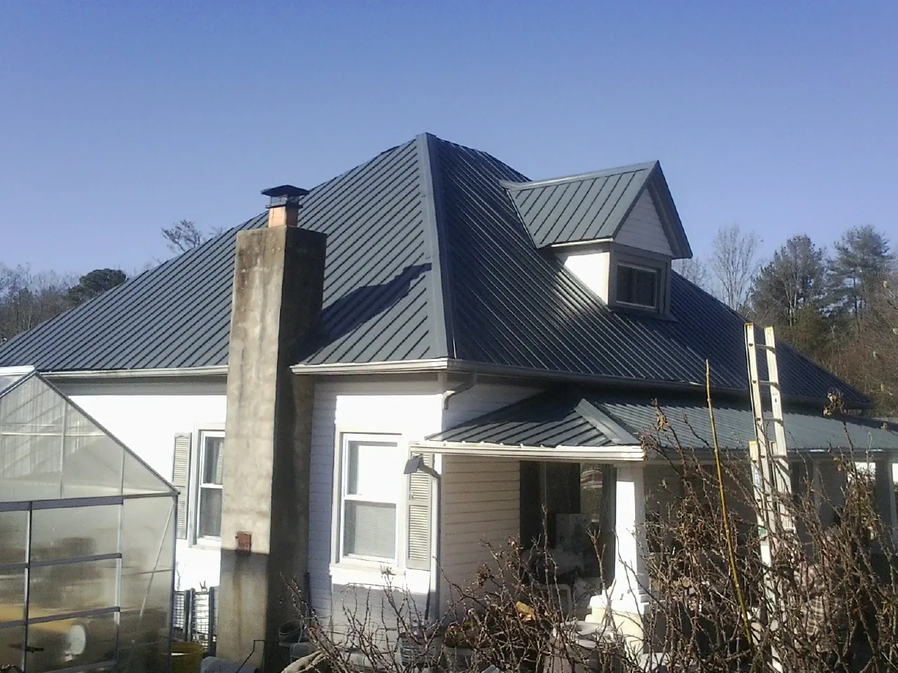 Dark blue standing seam metal roof on a white farmhouse with dormer — Slate & Tile Roof Repair by Roofing Brothers in Nunica