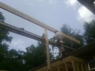 Carpenter setting a ridge beam over a new addition frame — Ice Dam Removal by Roofing Brothers in Nunica
