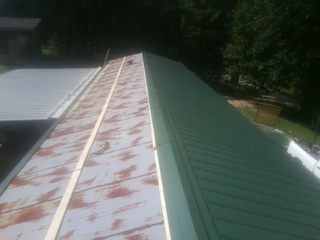 Old rusted panels beside newly installed green metal roofing — Wind Damage Roof Repair by Roofing Brothers in Nunica