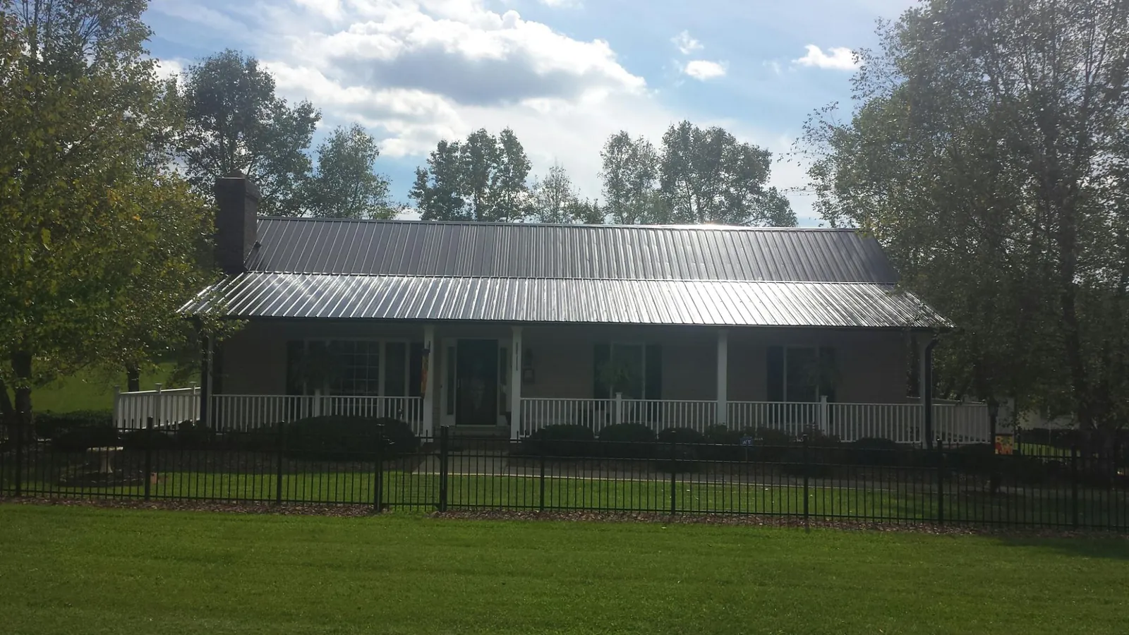 Gray metal roof on a brick ranch with a full width front porch — Gutter Guard Installation work by our crew in Nunica