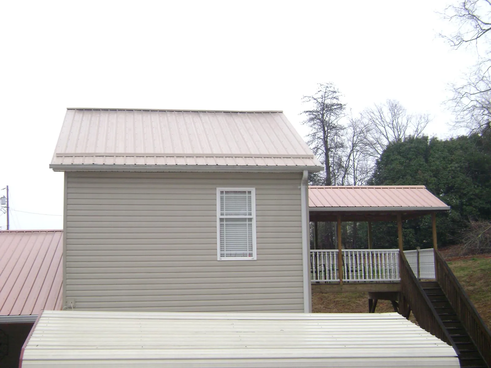 Tan metal roofs on a two story addition and attached porch, from a Roof Replacement job in Nunica