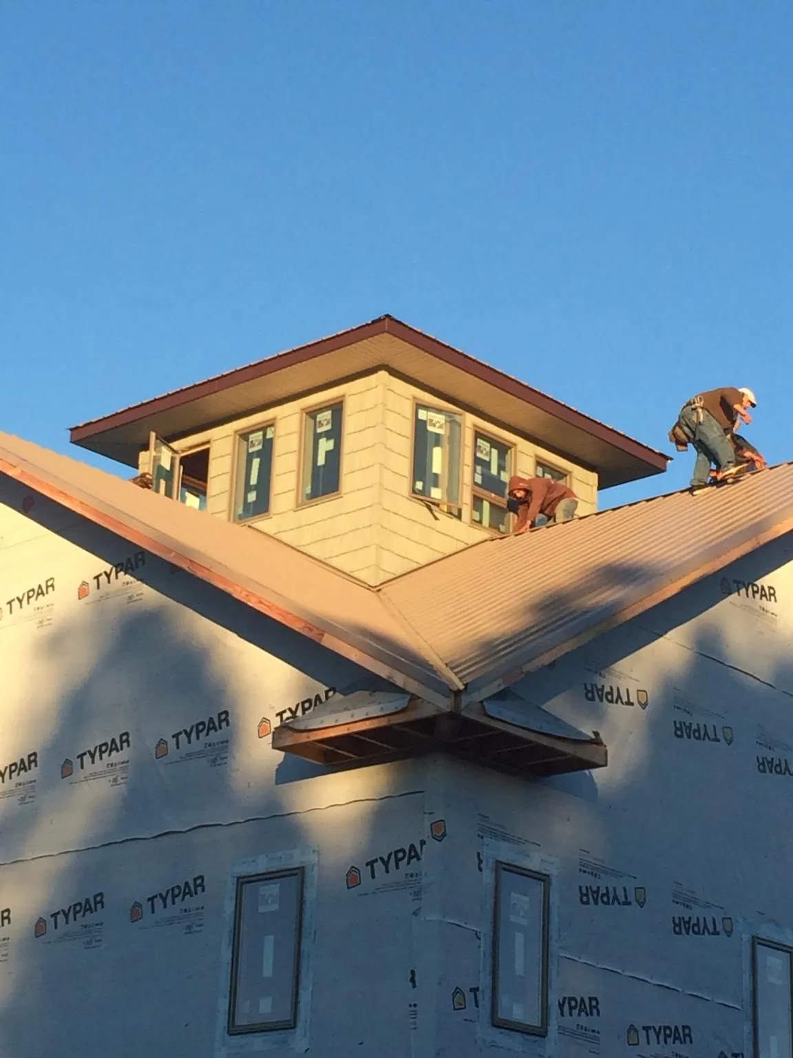 Roofers working around a rooftop cupola on a new metal roof at sunset — Roof Waterproofing in Nunica by Roofing Brothers